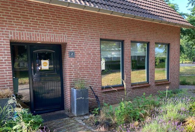 Wit geschilderde serre met kozijnen aan de zijgevel
