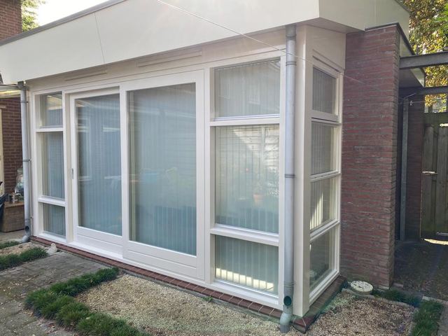 Wit geschilderd kozijn met balkon op een lichte gevel