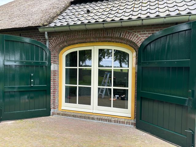 Groen geschilderde stal- of garagedeuren met geel kozijn