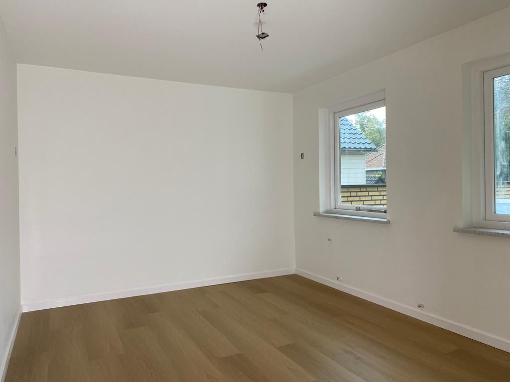 Strak wit geschilderde binnenkamer met houten vloer
