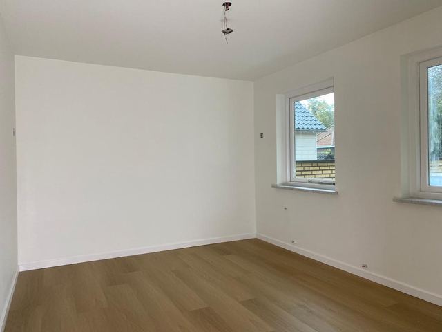 Strak wit geschilderde binnenkamer met houten vloer